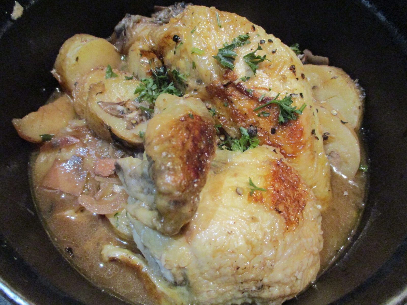 Golden chicken braised in a vinegar sauce with potatoes in a cast-iron pot