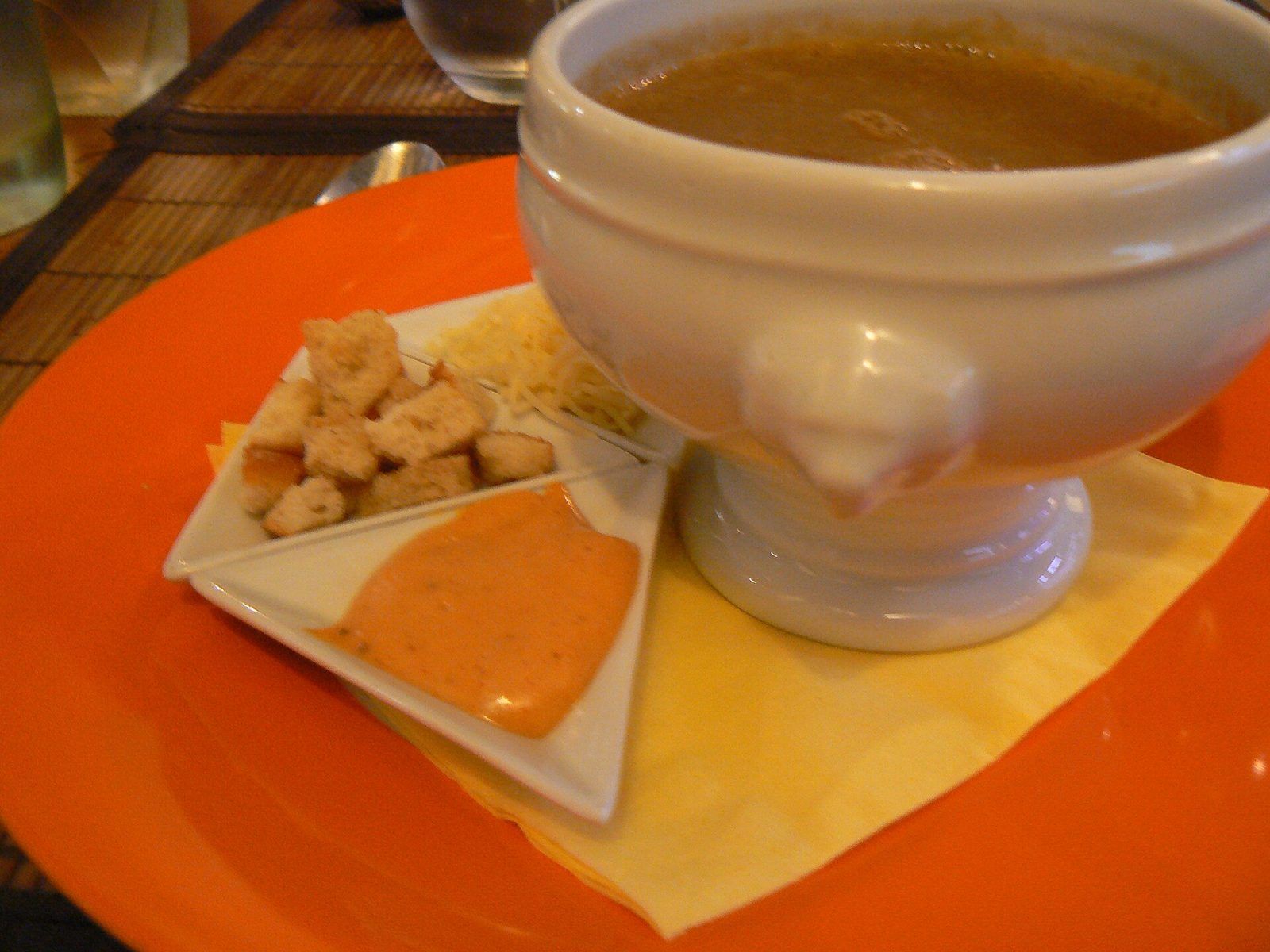 Fish soup in a footed bowl, served with rouille, croutons and grated cheese on the side