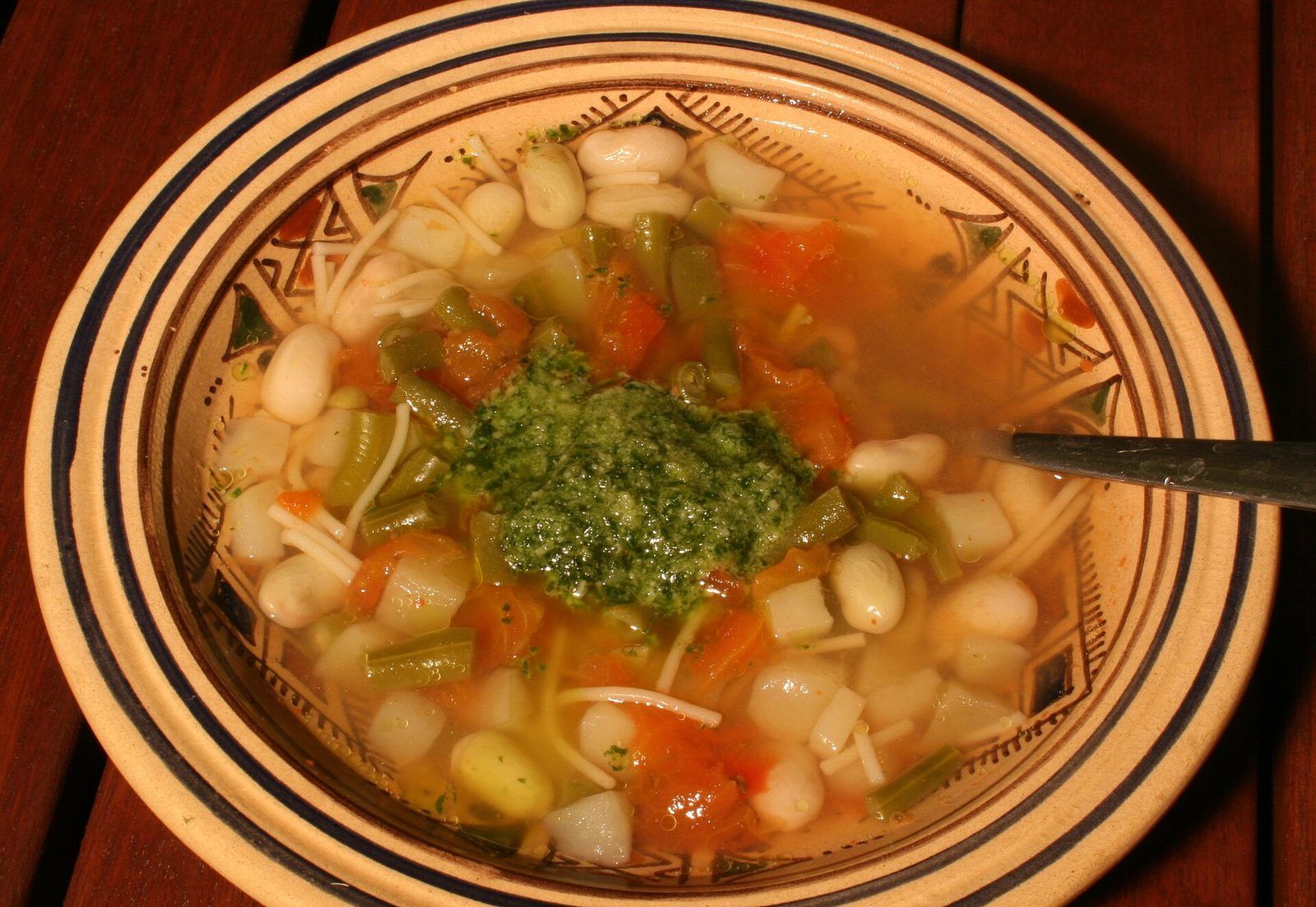 Bowl of soupe au pistou with white beans, green beans, vermicelli and a spoonful of green pistou