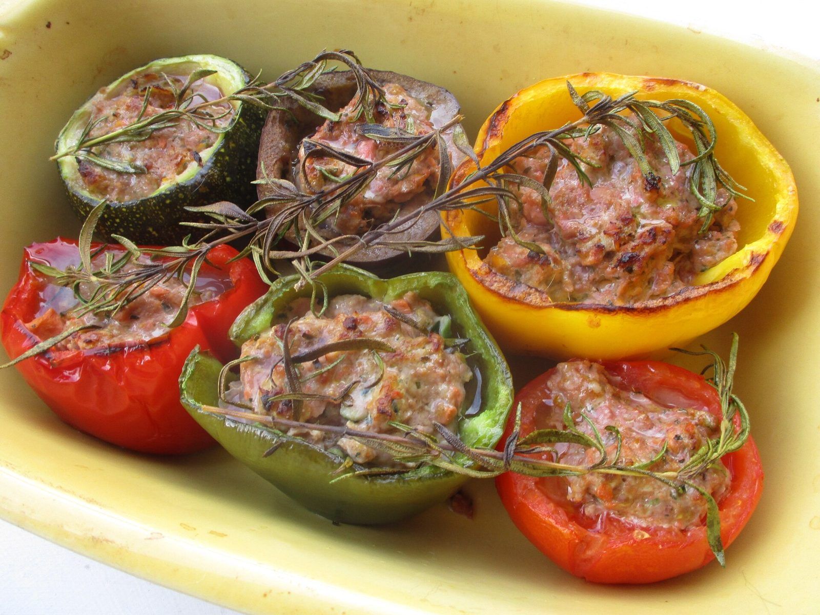 Stuffed tomatoes, peppers, courgettes and aubergine with rosemary in a baking dish